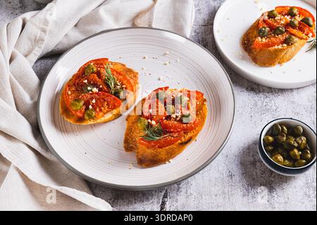 Italian crostini with sun-dried tomatoes, capers and spices on a plate on a table Stock Photo