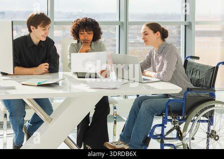 Teamwork brainstorm. Diverse multiracial colleagues woman in chair for people with disability working together. Group of people Stock Photo