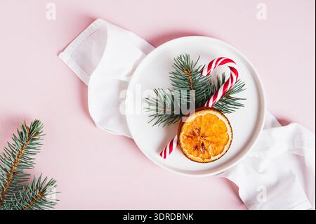 Close up of christmas table setting lollipop, fir tree and dried orange on plate on table top view Stock Photo