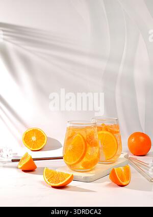 Orange juice and oranges on elegant kitchen table with long hard shadows. Modern still life with citrus fruits, minimal detox di Stock Photo