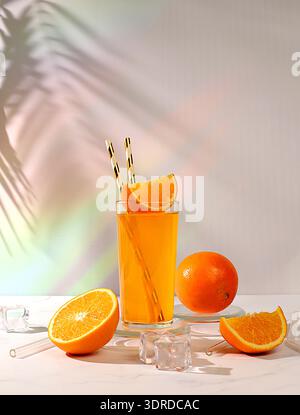 Orange juice and oranges on sunny kitchen table with long hard shadows. Modern still life with citrus fruits, minimal detox diet Stock Photo