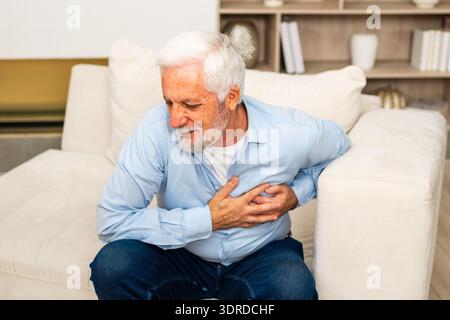 Pain on heart, heart attack. Unhappy middle aged senior man suffering from chest pain heart attack problems with health at home. Stock Photo