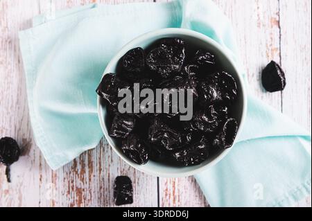 Close up of sweet dried prunes in bowl and jar on table top view Stock Photo