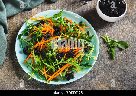 Vegetarian salad with prunes, herbs and carrots on a plate on the table Stock Photo
