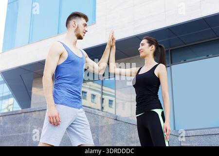 Couple Engages in Fitness and Exercise Routine Outdoors on a Sunny Day Near a Modern Building Stock Photo