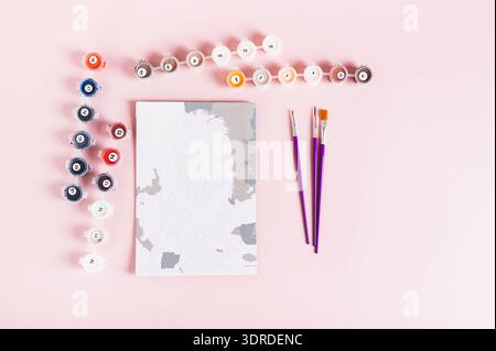 Paint by numbers kit and started painting on pink background top view Stock Photo
