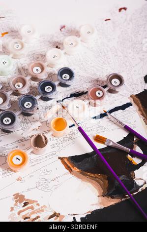 Set of multi-colored acrylic paints, brushes and canvas for painting by numbers vertical view Stock Photo