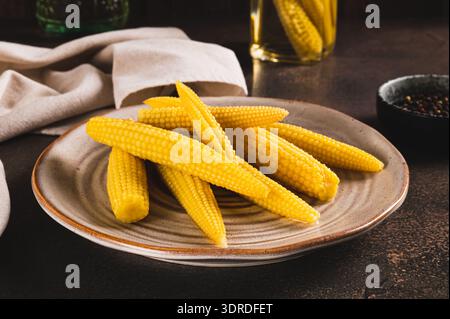 Canned mini corn cobs on a plate on a table Stock Photo