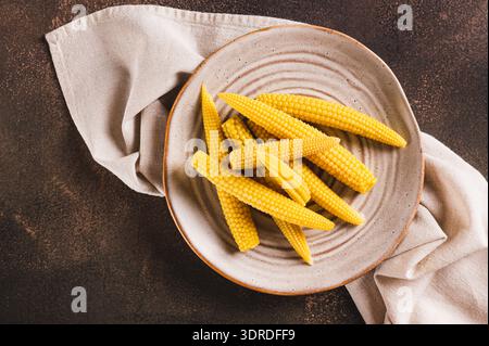 Close up of canned mini corn cobs on a plate on a table top view Stock Photo
