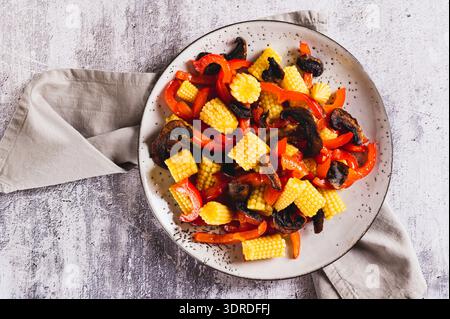 Close up of appetizing salad of canned corn, fried mushrooms and peppers on a plate top view Stock Photo