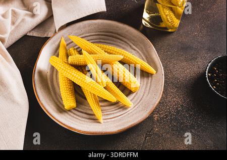 Portion of canned corn on the cob on a plate and in a jar on a table Stock Photo