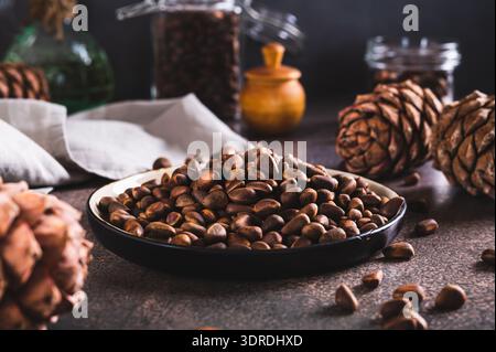 Ripe pine nuts in the shells on a plate and boiled pine cones on the table Stock Photo