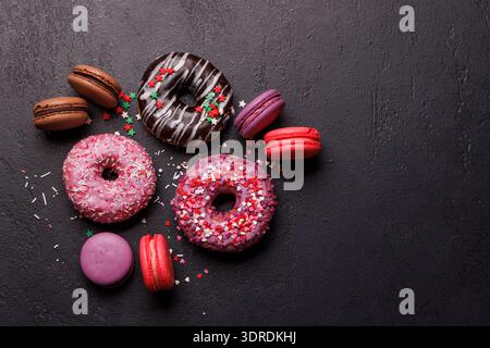 An eye-catching arrangement of colorful macarons and donuts on a dark background Stock Photo