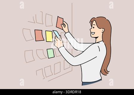 Business woman stands near scrum board with stickers and is engaged in kanban task planning Stock Photo