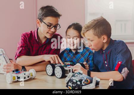 Kids Work Together to Build and Program Robots in a Classroom Setting During Afternoon Stock Photo