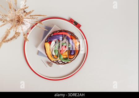 Scissors on basket with colored embroidery threads in hoops on gray background top view Stock Photo