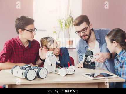 Kids Learn Robotics With Teacher in Classroom Setting During Afternoon Session Stock Photo