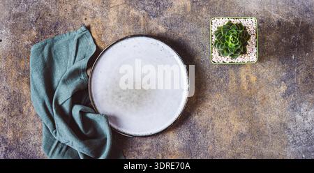 Ceramic empty plate, napkin and potted succulent on textured gray background top view web banner Stock Photo
