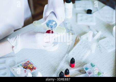 Female hands in gloves fill a measuring mold from a bottle with epoxy resin Stock Photo