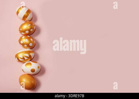 Decorated golden easter eggs on a pink background. Minimal holiday concept. Happy easter background. Creative painting of eggs a Stock Photo