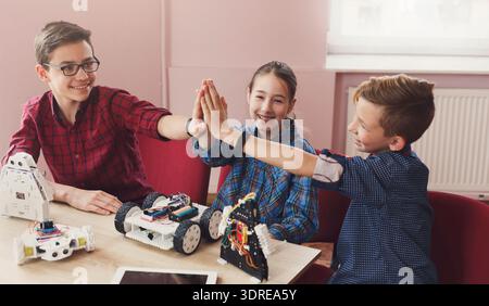 Kids Enjoy Teamwork While Building and Programming Robots in a Classroom Setting Stock Photo