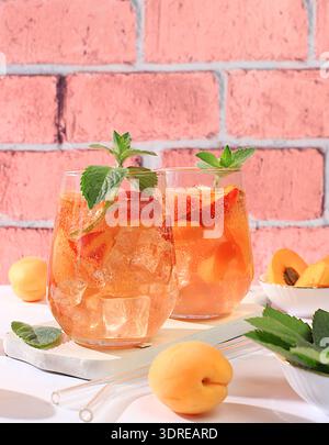 Ice peach tea or cocktail with mint and apricots, a recipe for a refreshing summer drink. Two glasses with peach fruit lemonade Stock Photo