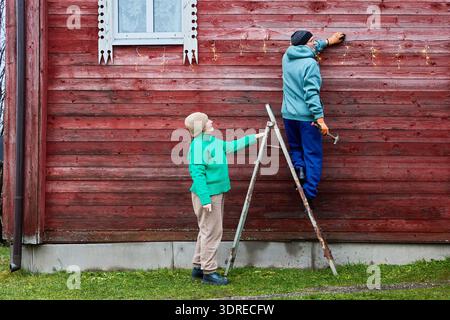 Installing string lights on facade of wooden farm building. Stock Photo