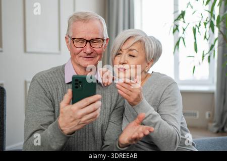 Video call. Happy senior couple woman man with smartphone having video call. Mature old grandmother grandfather talking speaking Stock Photo