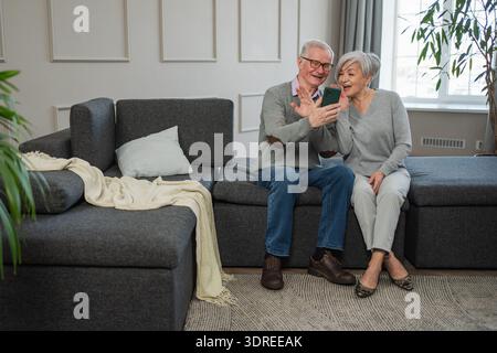 Video call. Happy senior couple woman man with smartphone having video call. Mature old grandmother grandfather talking speaking Stock Photo