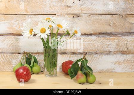 Bouquet with chamomiles and ripe apples and pears on a wooden table, rustic style.Abstract floral arrangement, autumn background Stock Photo