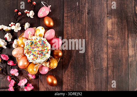 Abstract easter composition with traditional russian kulich with meringue and decorated painted eggs on wooden table with spring Stock Photo