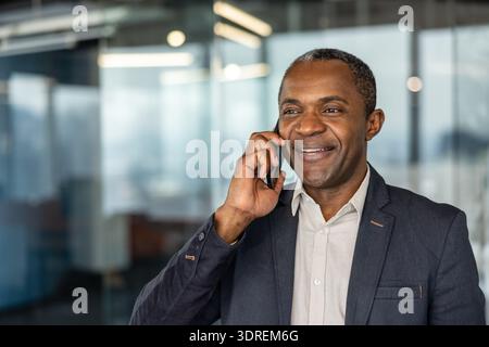 Confident mature professional man communicating cheerfully on a mobile phone, representing success, connection, and technology in a corporate environment Stock Photo