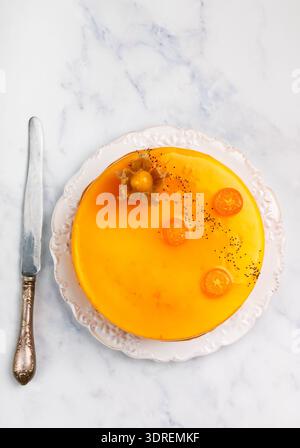 Mousse cake with orange and kumquat (apricot, passion fruit, peach, persimmon) on a white plate on a marble table. Cheesecake. D Stock Photo