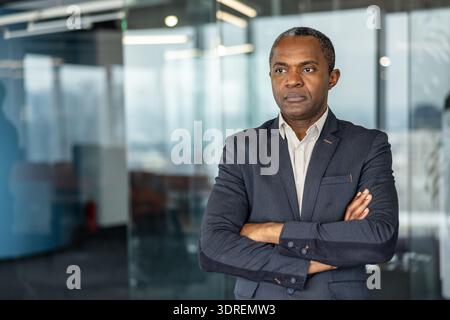 Confident executive man standing in a modern office building, representing leadership, professionalism, and corporate success while looking away with a thoughtful expression Stock Photo