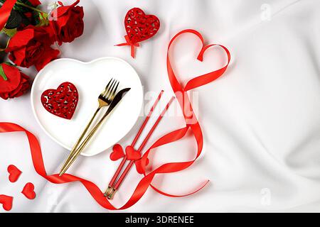 Festive table setting, menu layout for Valentine's day, cutlery with a heart on a plate on a marble background, festive composit Stock Photo