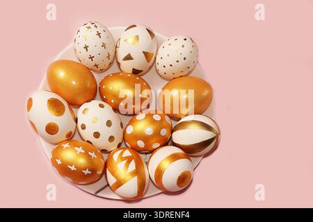 Decorated golden easter eggs on a pink background. Minimal holiday concept. Happy easter background. Creative painting of eggs a Stock Photo