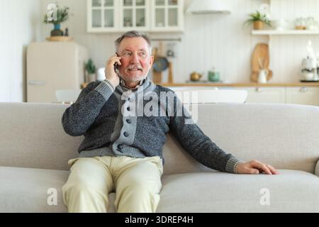 Happy middle aged senior man talking on smartphone with family friends. Older mature grandfather with cell phone talking with gr Stock Photo