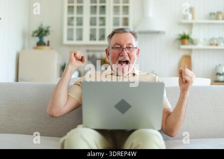 Excited middle aged senior man euphoric winner. Older mature grandfather looking at laptop reading great news getting good resul Stock Photo
