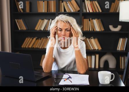 Headache pain. Middle aged woman touching temples experiencing stress. Mature old lady tired of work feeling headache sick rubbi Stock Photo