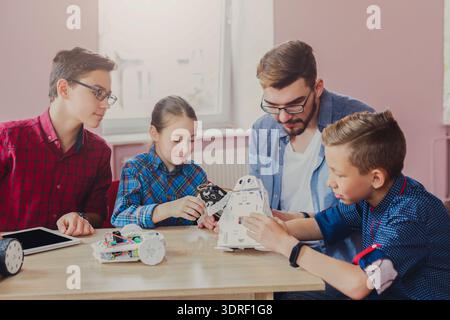 Kids Learn About Robotics With Teacher in Classroom During Afternoon Activities Stock Photo