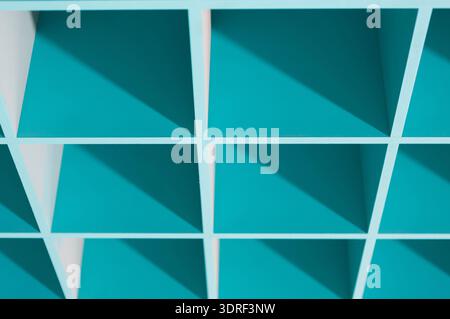 Shelving Unit With Turquoise Compartments and Clear Shadows on a White Wall Stock Photo