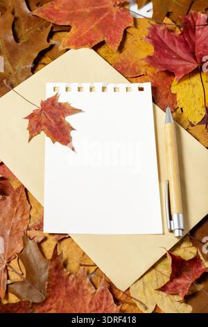 Autumn letter. Blank paper with envelope and bamboo pen over fallen leaves background Stock Photo