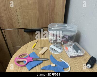 A tailor's sewing kit on a table. Needles, thread, and fabric for sewing. Stock Photo