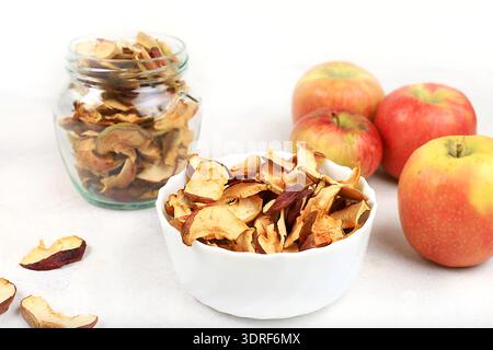 Homemade apple chips in a cup and a jar of apples on a white background, in the fall apples are baked in the oven or dryer for s Stock Photo