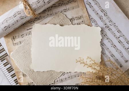 Blank vintage paper card on aged music notes background. Empty grunge postcard with copy space. Retro composition Stock Photo