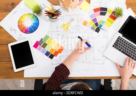 Working on a Design Project With Color Palettes and Blueprints on a Wooden Table Stock Photo