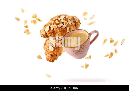 Fresh baked almond  breakfast croissants  with nuts flakes crumbs, pink vintage cup of hot coffee  flying isolated on white background. Two croissants Stock Photo