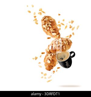 Fresh baked almond  breakfast croissants  with nuts crumbs and black cup hot coffee flying isolated on white background. Three croissants falling. Pas Stock Photo