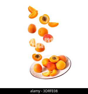 Fresh ripe whole  and sliced apricot fruits falling on vintage plate isolated on white background. Flying food Stock Photo