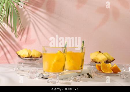 Cocktail or punch of tequila, rum and vodka with pineapple slices, orange, ice and rosemary. Summer party concept. Diet drink fo Stock Photo